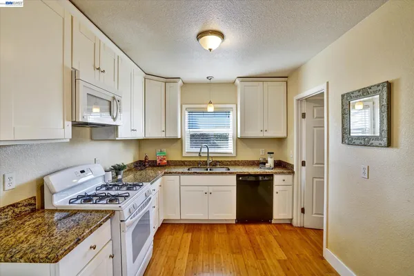 a kitchen with stainless steel appliances granite countertop a stove a sink dishwasher and a refrigerator