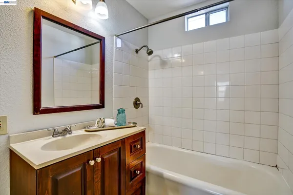 a bathroom with a sink vanity tub shower and a mirror
