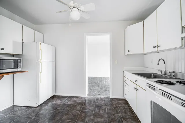 a kitchen with sink a refrigerator and white cabinets