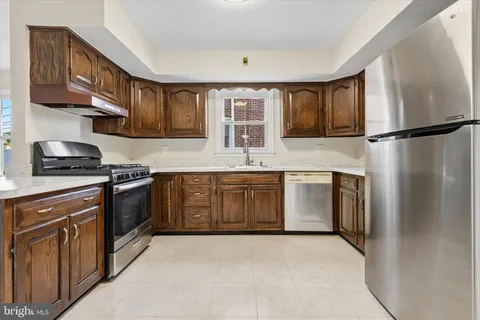 a kitchen with a stove top oven a sink and dishwasher a refrigerator with wooden cabinets