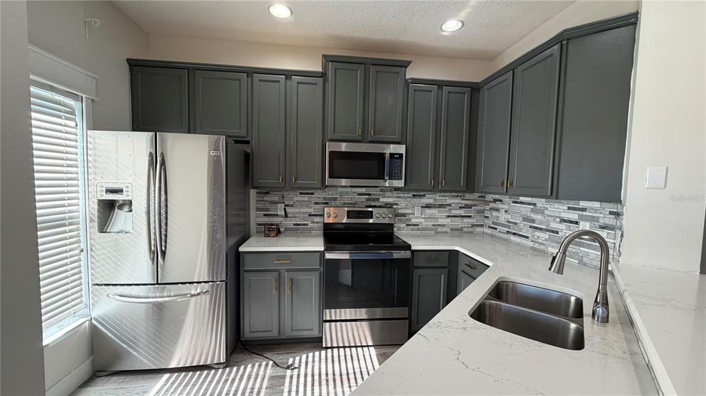 1941 Brancaster Circle Ocoee, FL 34761 - Photo 8 of 33 a kitchen with granite countertop a refrigerator stove and sink