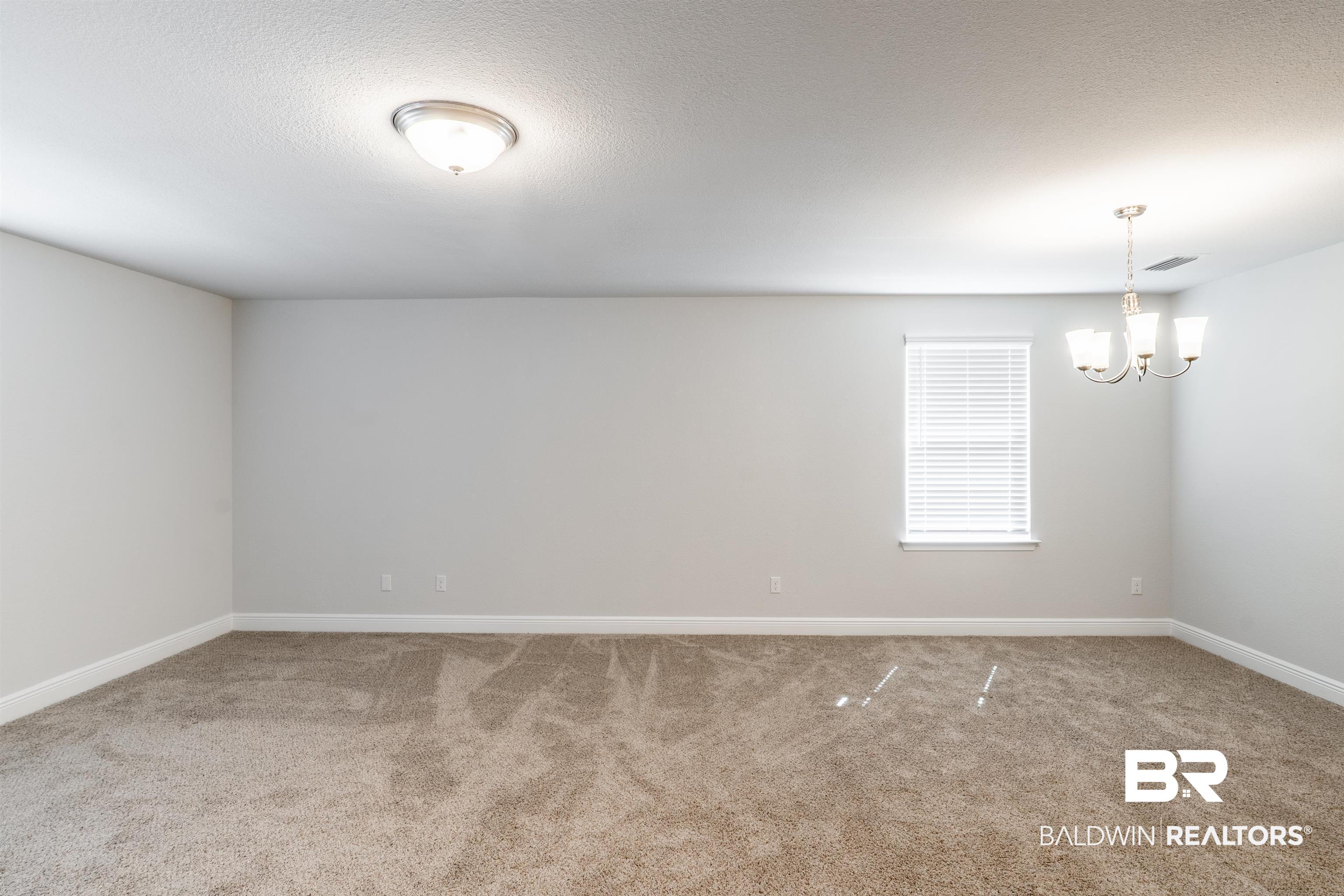 1906 Stonepine Drive South Semmes, AL 36575 - Photo 8 of 30 Spare room featuring light carpet, a chandelier, and a textured ceiling
