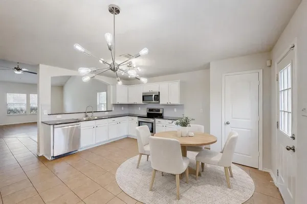 a kitchen with stainless steel appliances kitchen island granite countertop a sink a microwave a dining table and chairs