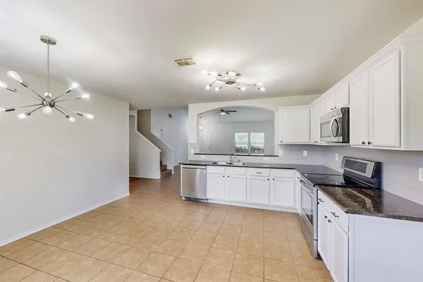 a large kitchen with stainless steel appliances a stove sink and cabinets