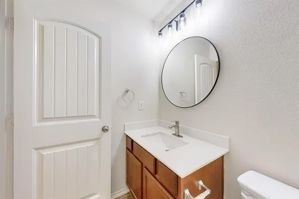 a bathroom with a sink vanity mirror and toilet