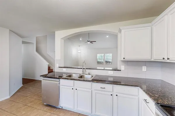 a kitchen with granite countertop white cabinets and a sink