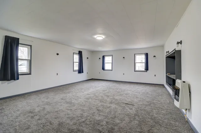 a view of an empty room with windows and fireplace