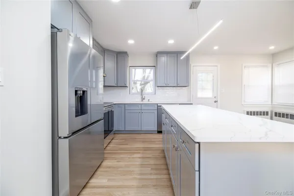 a large kitchen with stainless steel appliances kitchen island granite countertop a refrigerator and a sink