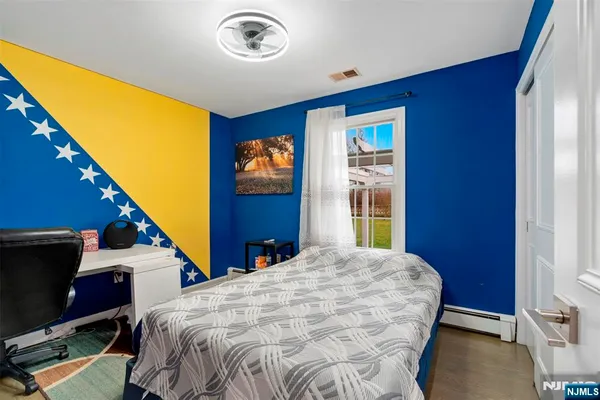 a bedroom with a bed and a flat tv screen on dresser