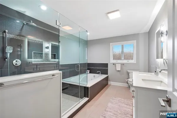 a bathroom with a double vanity sink a mirror a bathtub and shower