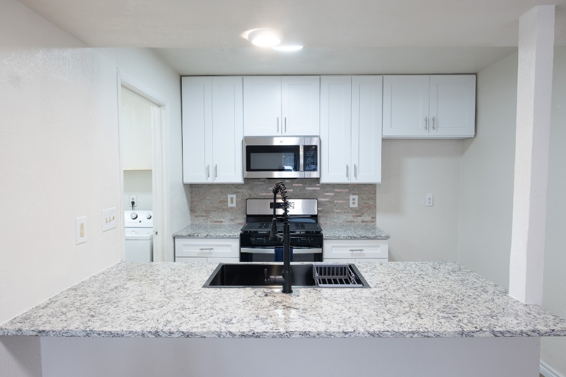 2401 Bucks Run, Unit A Austin, TX 78744 - Photo 12 of 33 a kitchen with granite countertop a stove a sink and a microwave