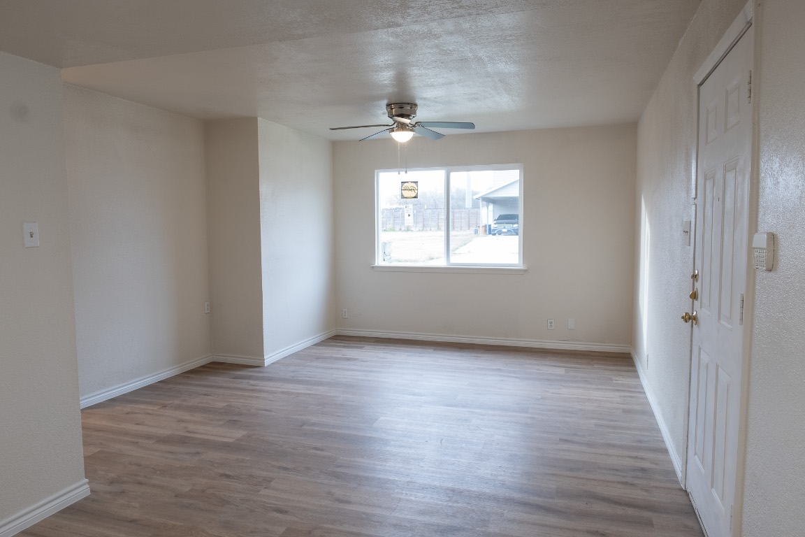 2401 Bucks Run, Unit A Austin, TX 78744 - Photo 15 of 33 an empty room with wooden floor chandelier and windows