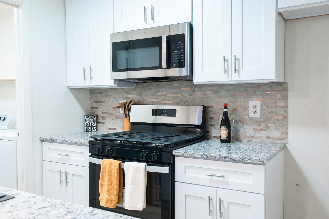 2401 Bucks Run, Unit A Austin, TX 78744 - Photo 22 of 33 a kitchen with granite countertop cabinets stove top oven and microwave