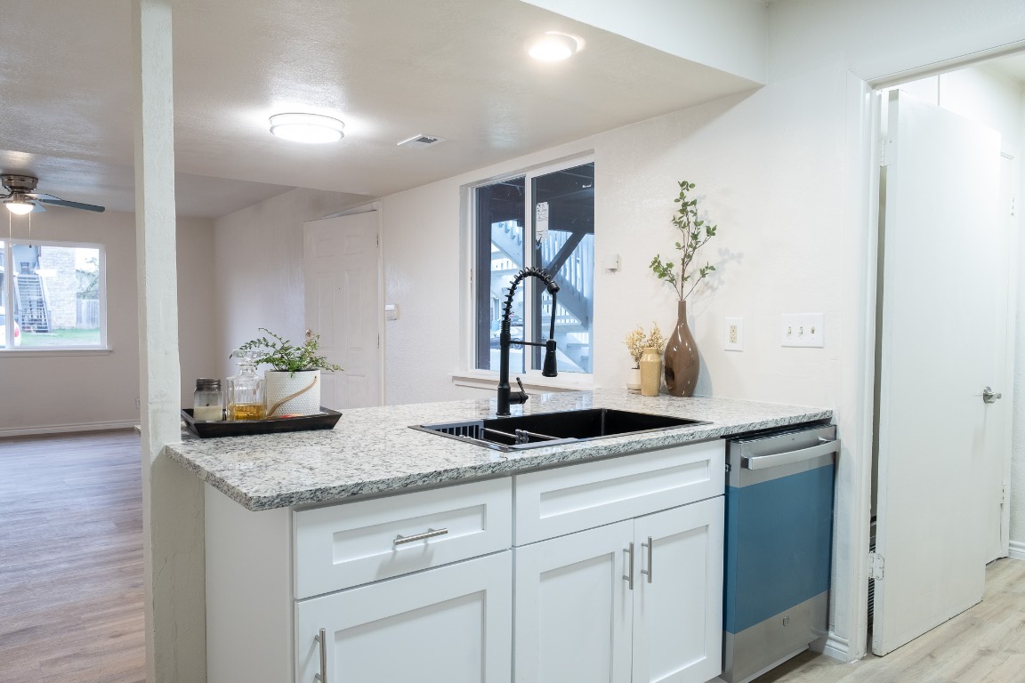 2401 Bucks Run, Unit A Austin, TX 78744 - Photo 3 of 33 Kitchen featuring light wood-style floors, white cabinets, dishwashing machine, light stone counters, and a ceiling fan