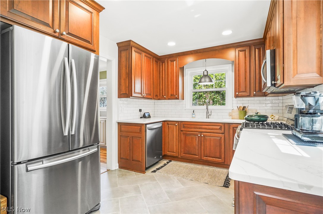 474 Malvern Road Akron, OH 44303 - Photo 27 of 47 Kitchen with decorative light fixtures, backsplash, stainless steel appliances, light tile floors, and light stone counters