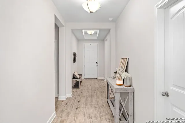 a view of a hallway with wooden floor and a bathroom
