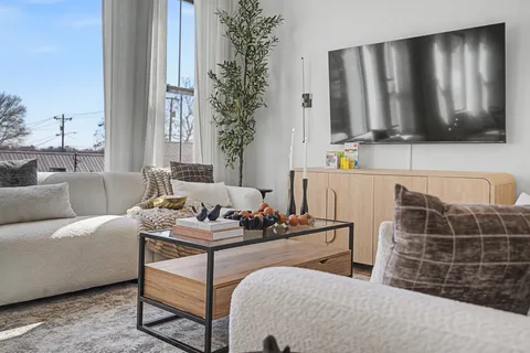 a living room with furniture a flat screen tv and a window