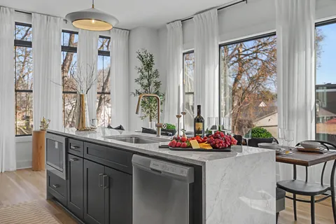 a kitchen with stainless steel appliances kitchen island granite countertop a refrigerator a stove a sink dishwasher and a dining table with wooden floor