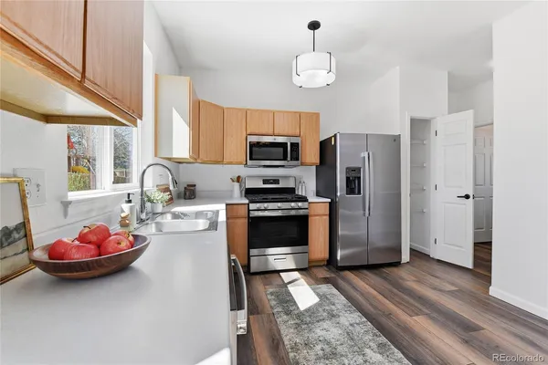 a kitchen with stainless steel appliances granite countertop a refrigerator a sink a stove and white cabinets
