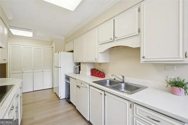 a kitchen with white cabinets a sink dishwasher and a stove with wooden floor