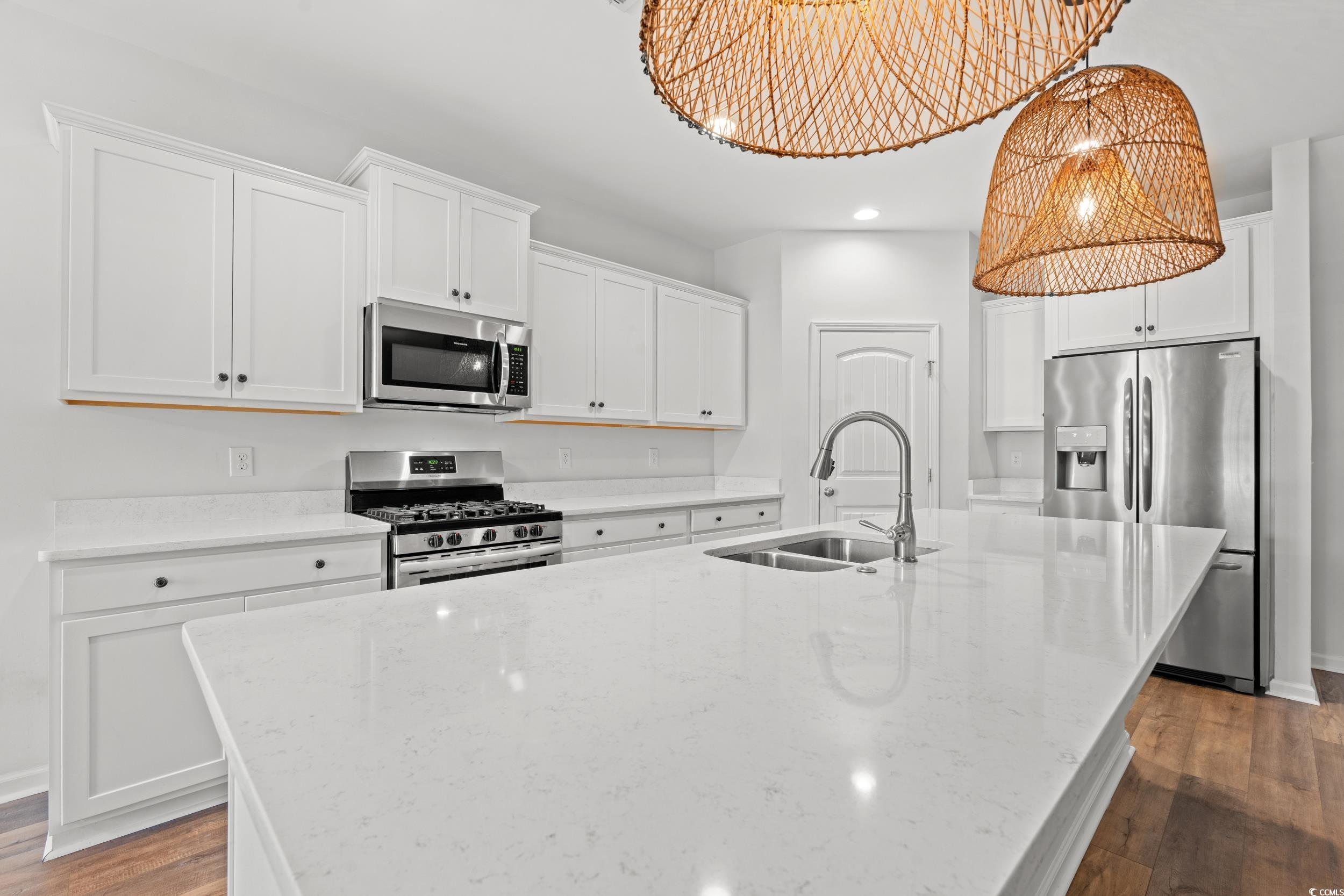 3026 Millstone Place Georgetown, SC 29440 - Photo 13 of 34 Kitchen featuring stainless steel appliances, a spacious island, dark wood-style floors, white cabinets, and light stone counters