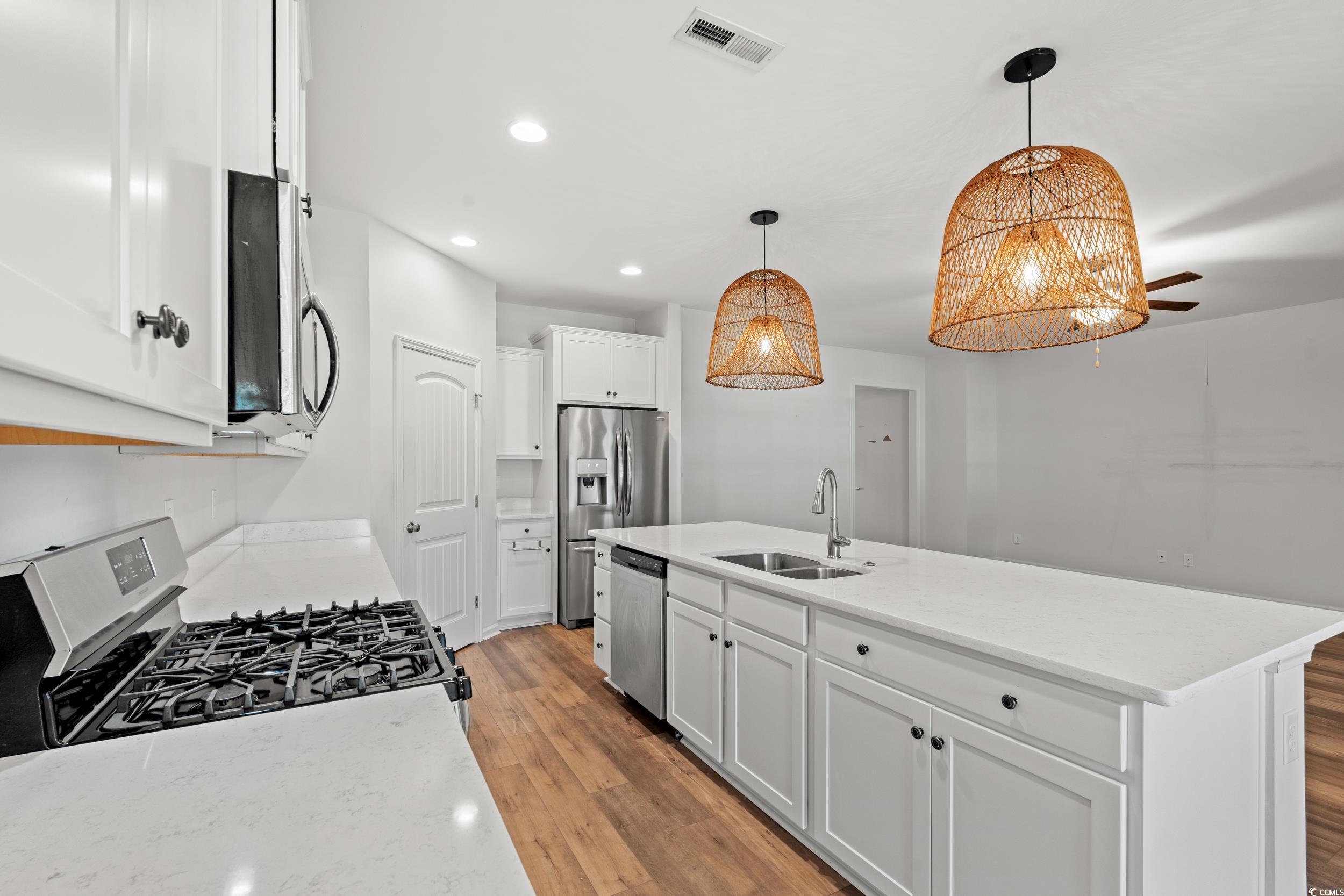 3026 Millstone Place Georgetown, SC 29440 - Photo 14 of 34 Kitchen with appliances with stainless steel finishes, light wood-type flooring, white cabinets, recessed lighting, and hanging light fixtures
