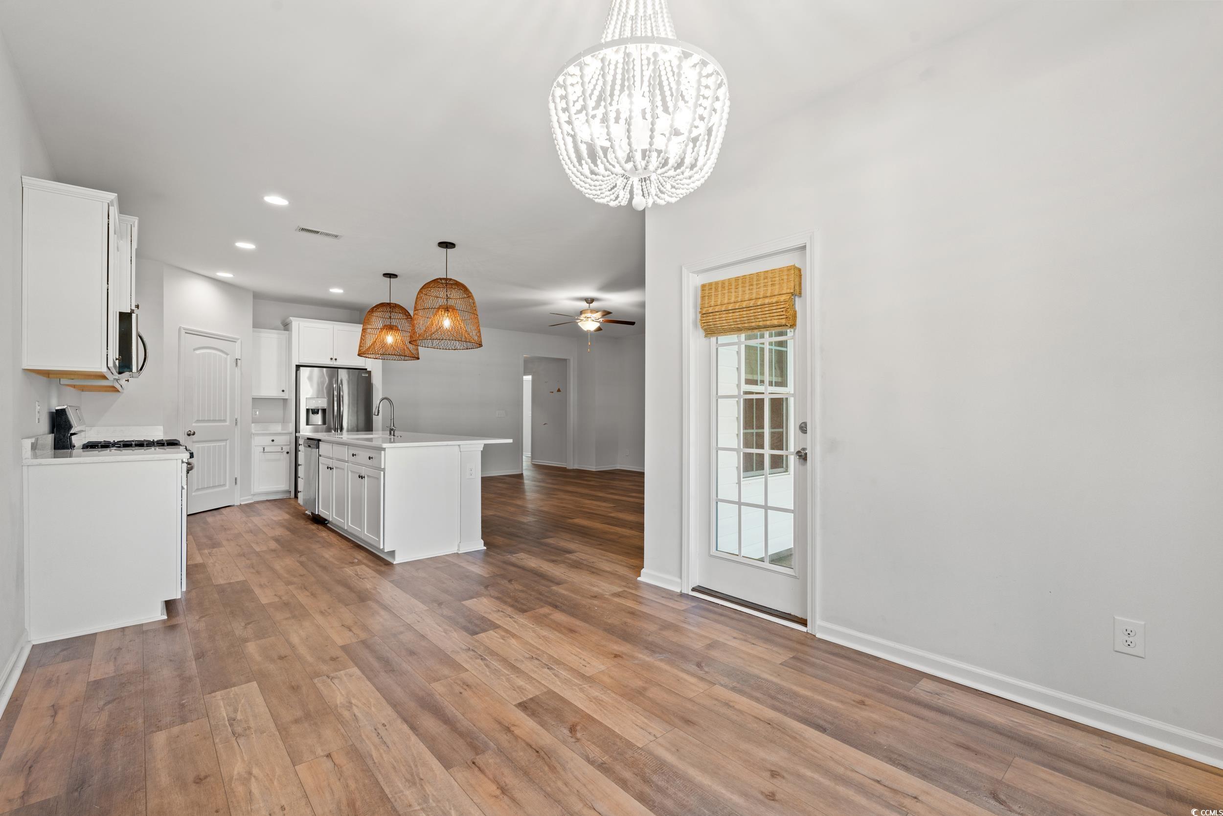 3026 Millstone Place Georgetown, SC 29440 - Photo 32 of 34 Kitchen with a chandelier, open floor plan, LVP Flooring, white cabinetry, and a center island with sink