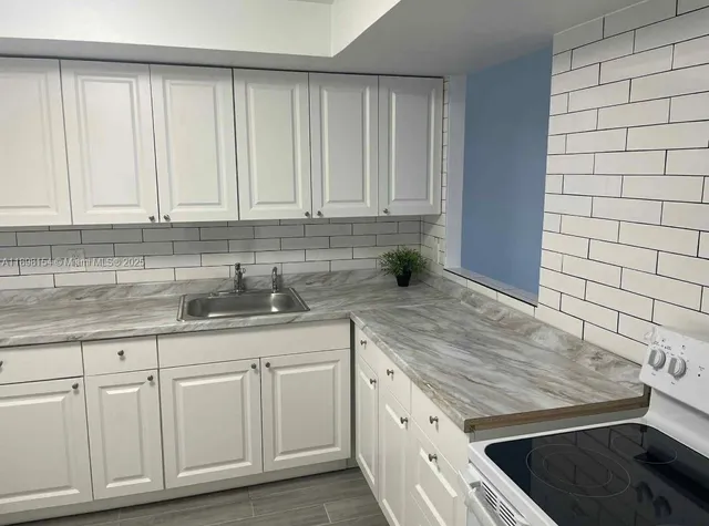 a kitchen with granite countertop white cabinets and sink