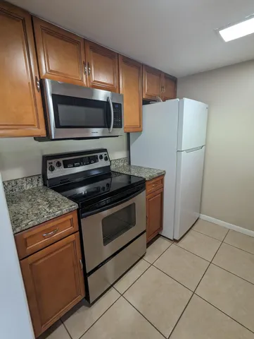 a kitchen with granite countertop a refrigerator and a stove top oven