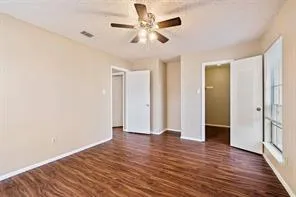 an empty room with wooden floor and a ceiling fan