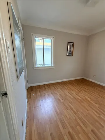 a view of an empty room with wooden floor and a window