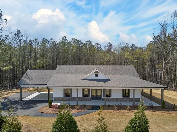 an aerial view of a house with swimming pool and trees in the background
