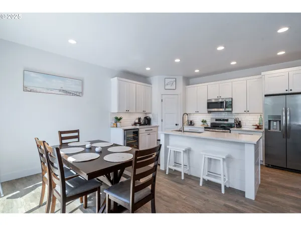 a open dining room with stainless steel appliances kitchen island granite countertop a dining table chairs and a refrigerator