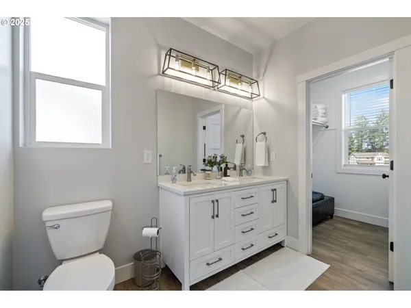 a bathroom with a toilet a sink a large mirror and a window