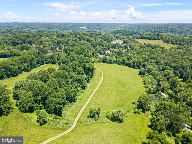 an aerial view of residential houses with outdoor space and trees all around