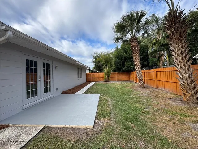 a backyard of a house with wooden floor and tree