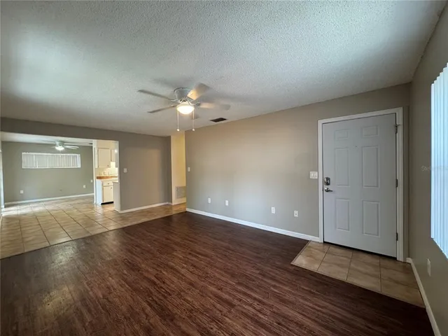 an empty room with wooden floor and chandelier fan