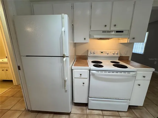 a white refrigerator freezer and a stove sitting inside of a kitchen