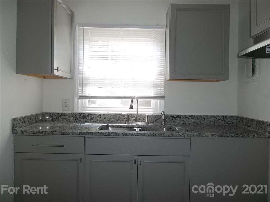 a kitchen with granite countertop a sink window and cabinets