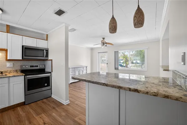 a kitchen with kitchen island granite countertop stainless steel appliances a stove sink and microwave