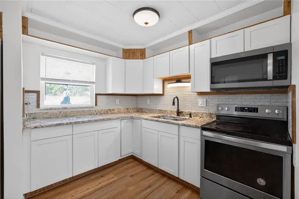 a kitchen with granite countertop wooden cabinets stainless steel appliances and a window