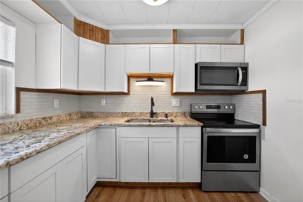 a kitchen with granite countertop white cabinets and stainless steel appliances