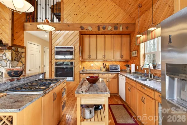 a kitchen with stainless steel appliances granite countertop a stove a sink dishwasher and cabinets with wooden floor