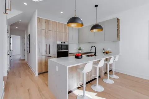 a kitchen with kitchen island stainless steel appliances granite countertop a stove a sink a dining table and chairs with wooden floor