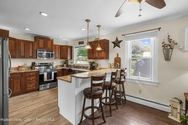 a kitchen with stainless steel appliances granite countertop a stove top oven a sink dishwasher a dining table and chairs with wooden floor