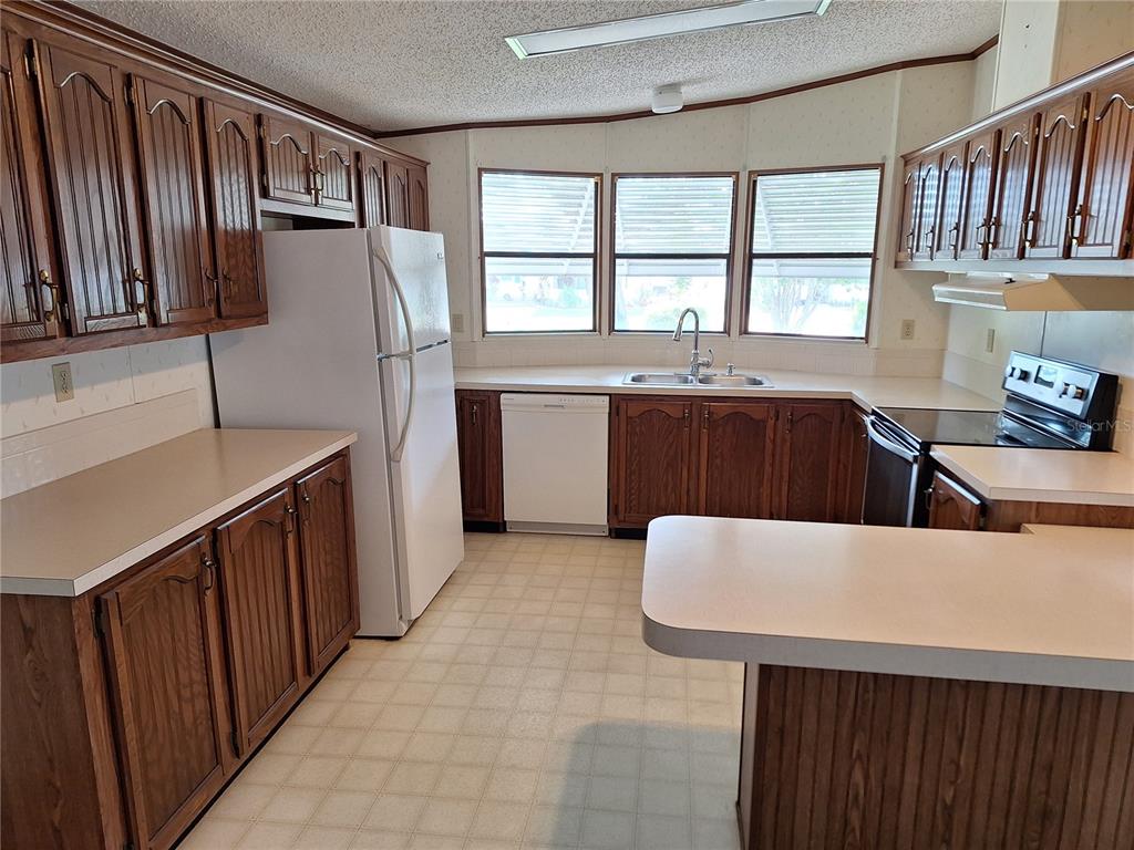 432 Santa Fe Road Tavares, FL 32778 - Photo 13 of 41 a large kitchen with stainless steel appliances granite countertop a sink refrigerator and window