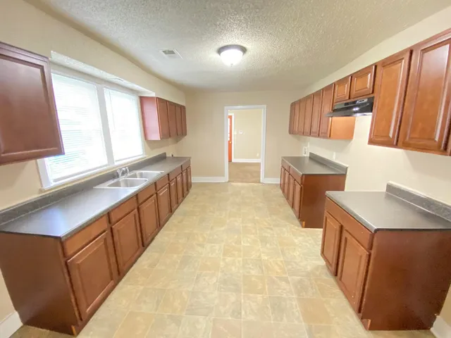 a kitchen with stainless steel appliances kitchen island wooden cabinets a sink a stove a refrigerator and a window