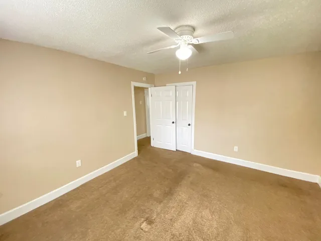 an empty room with a chandelier fan and a window