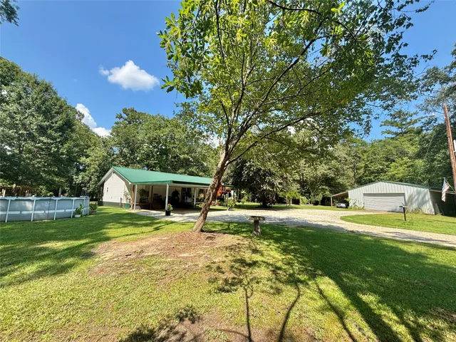 a view of a house with a big yard and potted plants and large trees