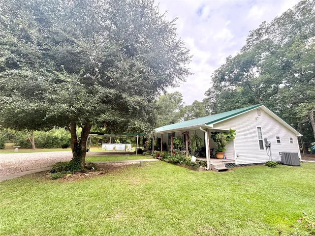 a view of a white house with a big yard and large trees